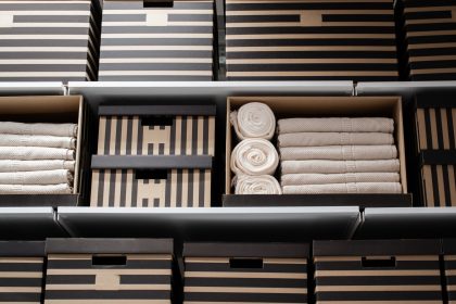 Cardboard striped boxes and white towels on hanging shelves. The concept of home storage